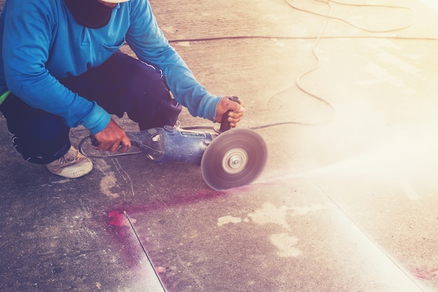 Close up hand man cutting concrete floor with machine.