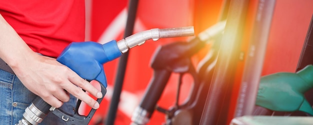 Foto mano di uomo che tiene l'ugello della pompa per il servizio alla stazione di servizio impiegato maschio lavoratore di rifornimento di carburante