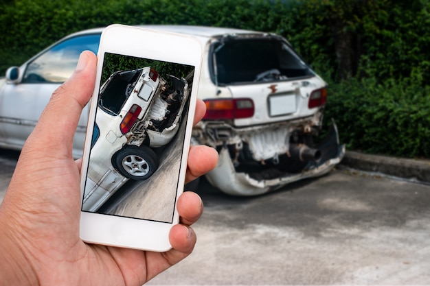 Foto chiuda sulla mano dello smartphone della tenuta dell'uomo e prenda la foto dell'incidente stradale