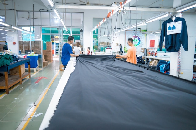 生地を敷設する人の手をクローズアップ工場で撮影した繊維布工場の作業プロセス仕立て労働者の機器