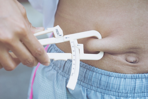 Close-up Of Hand measuring his body fat of sporty woman 