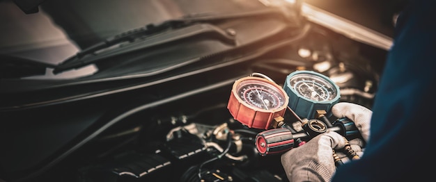 Close up hand of mechanic using manifold gauge check the refrigerant car air conditioner