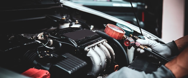 Close up hand of mechanic using manifold gauge check the refrigerant car air conditioner