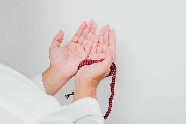 Close-up hand met een tasbih of gebedskralen op witte achtergrond