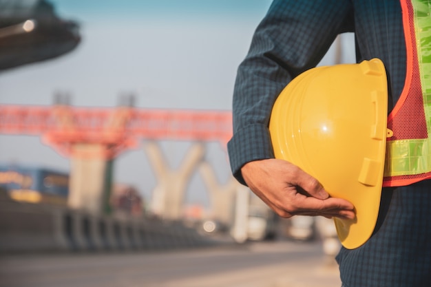 Close-up hand met harde hoed site bouw achtergrond, ingenieur architectuur helm beschermen