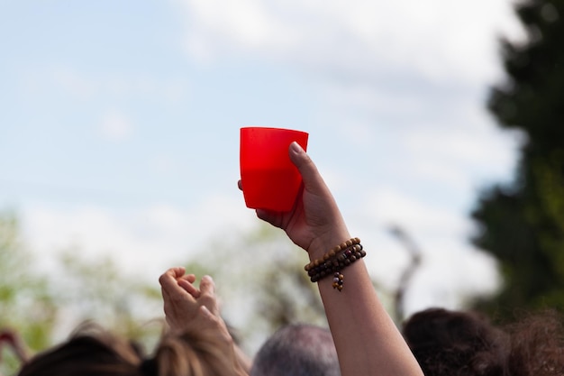 Close-up hand met rode plastic beker tijdens een concert