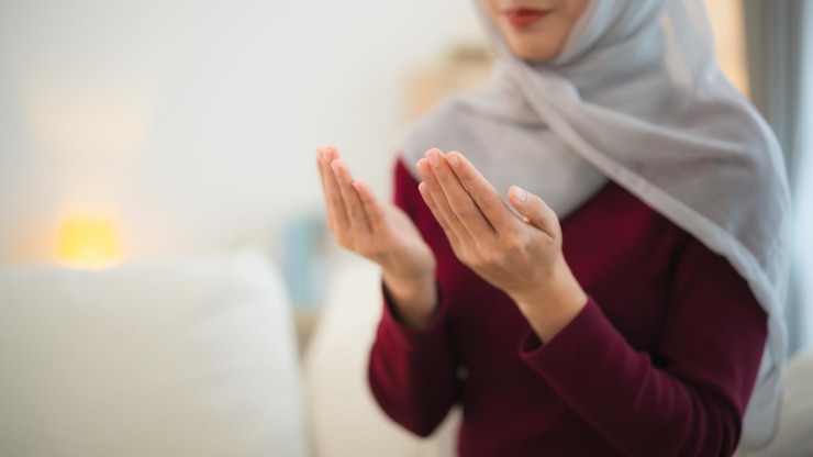 Photo 히자브를 입은 이슬람 여성은 하루 동안 기도하여 집에서 거실에서 기도하는 이슬람 여성의 신을 믿는 것을 보여줍니다.