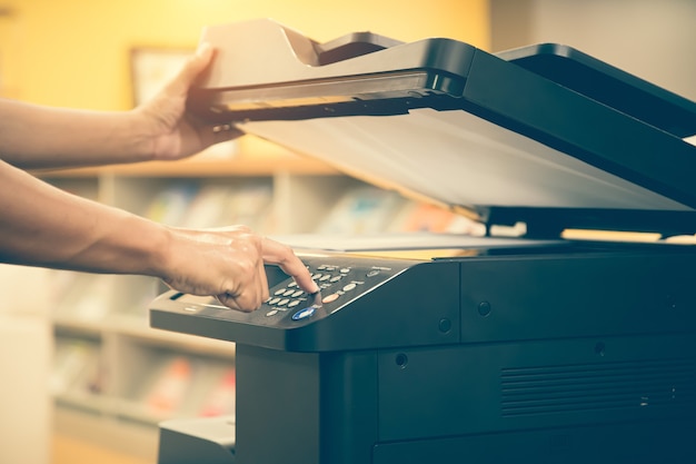 Foto chiudere la mano dell'uomo dell'ufficio premere il pulsante sulla fotocopiatrice.