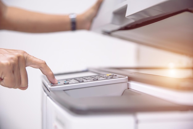 Close up hand of office man press the button on the copier