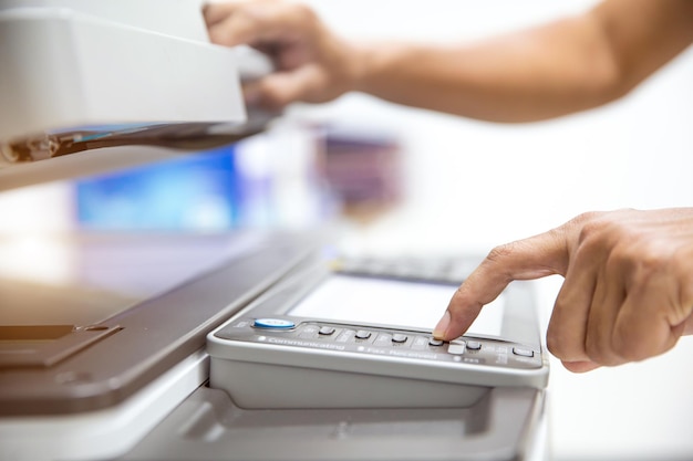 Close up hand office man press copy button on panel to using the photocopier