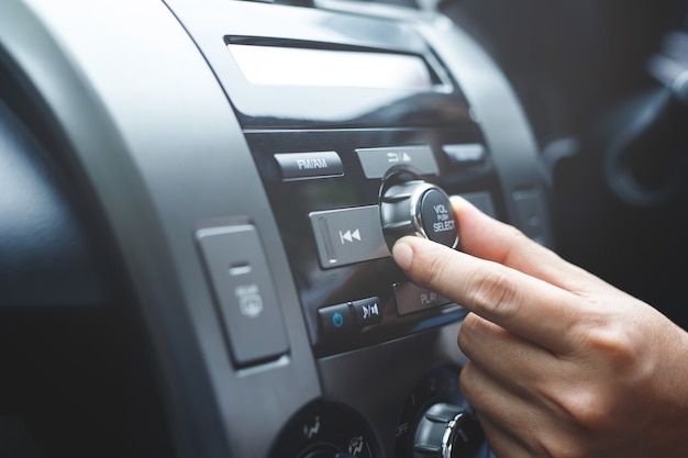 Close up hand open car radio listening. Car Driver changing turning button Radio Stations on His Vehicle Multimedia System. Modern touch screen Audio stereo System. transportation and vehicle concept