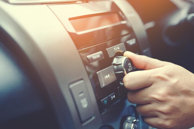 手を開くカーラジオを聞く車の運転手が回転ボタンを変更する彼の車のラジオ局マルチメディアシステム現代のタッチスクリーンオーディオステレオシステム輸送と車のコンセプト