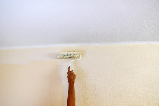 Close-up of hand painting wall at home