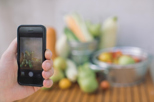 Photo close-up of hand photographing vegetables on table