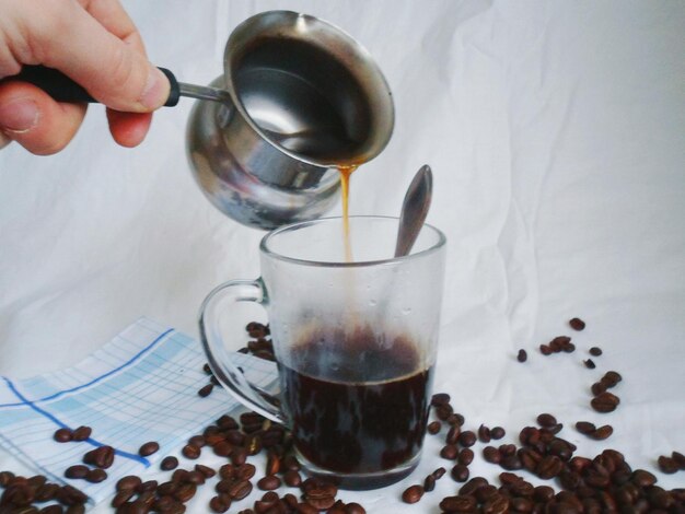 Foto close-up di una mano che versa il caffè in un bicchiere