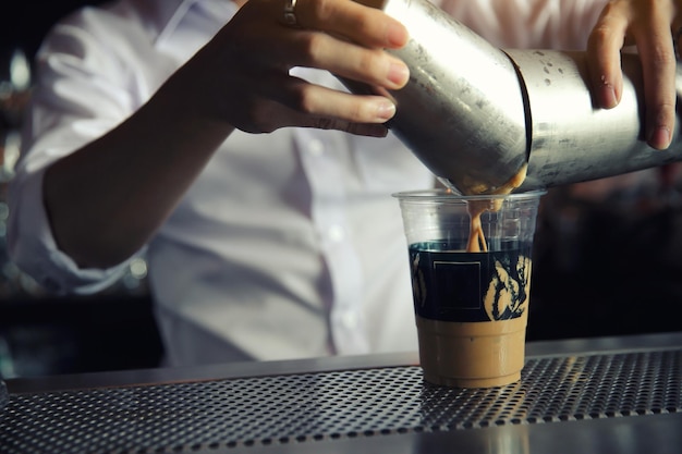 グラスにコーヒーを注ぐ手のクローズアップ