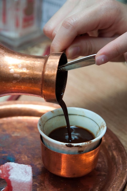 Photo close-up of hand pouring drink in cup