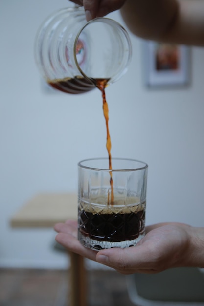 Close-up of hand pouring drink in glass