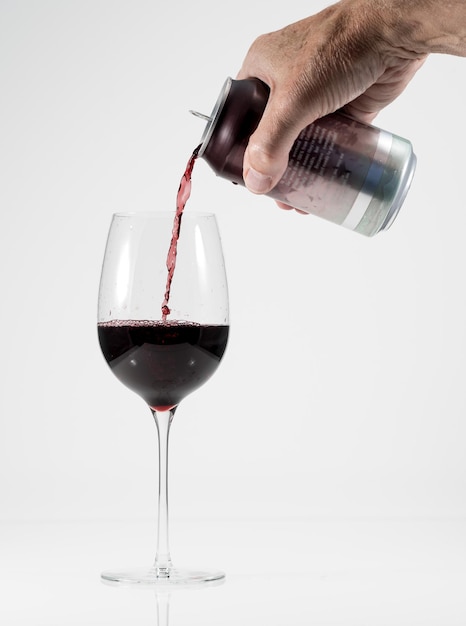 Photo close-up of hand pouring wine in glass against white background