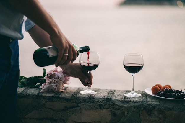 Photo close-up of hand pouring wine in glass