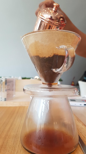 Close-up of hand preparing coffee on table at home