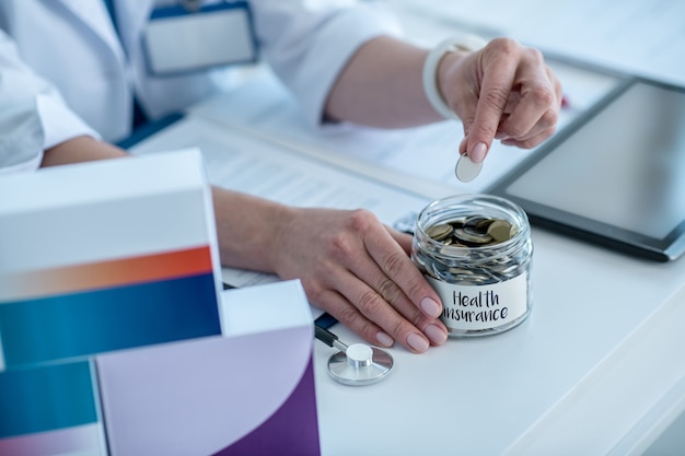 Close up of a hand putting coins into the jar