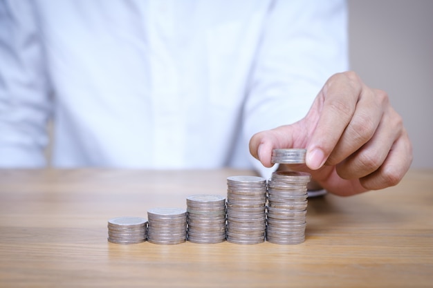 Photo close up hand putting coins stacks on the wooden table