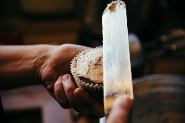 カップケーキにアイスをかけている手のクローズアップ