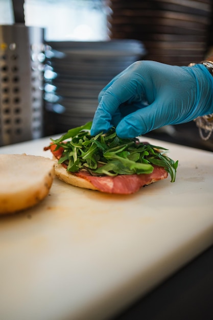 Close up of hand putting rocket leaves on bagel bread Brunch preparation