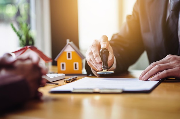 Close up hand of real estate agent holding a stamp to stamp approved in real estate purchase documents.