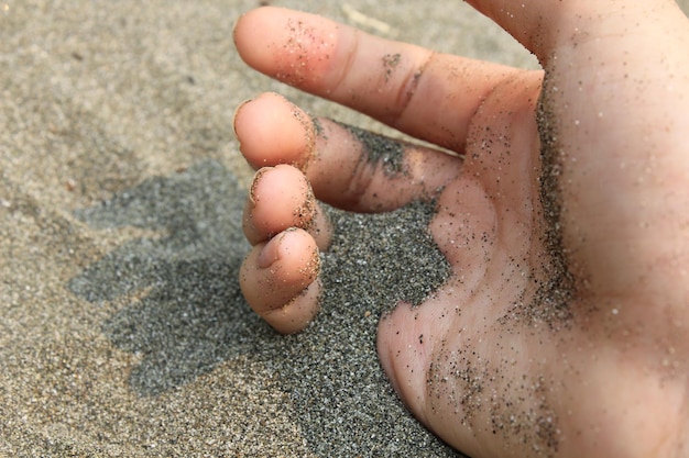 Foto close-up di una mano nella sabbia sulla spiaggia