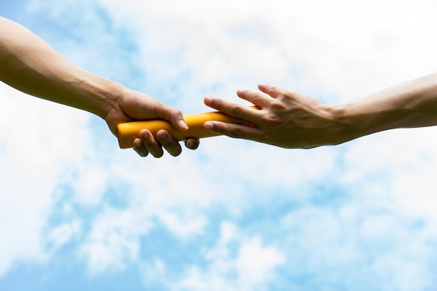 Close up hand set baton from hand to hand on sky background Business concept for teamwork and team builder