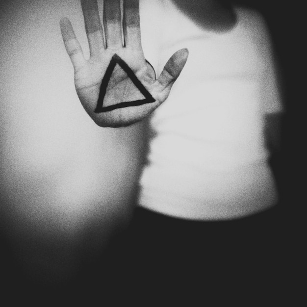 Photo close-up of hand showing triangle sign