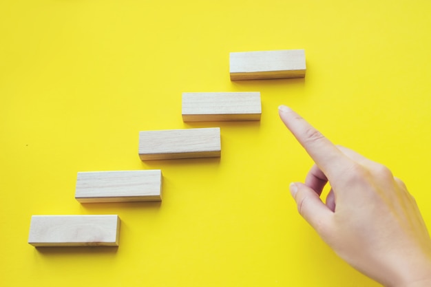 Foto mani ravvicinate su blocchi di legno impilati come scale a gradini. processo di successo della crescita del concetto di business