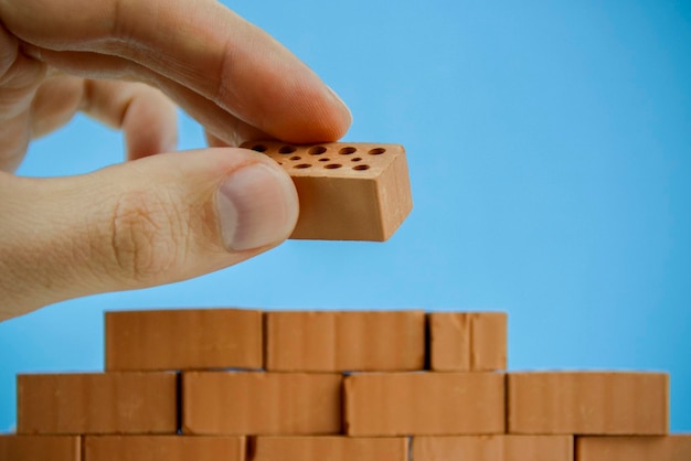 Close-up of hand stacking toy blocks against blue background