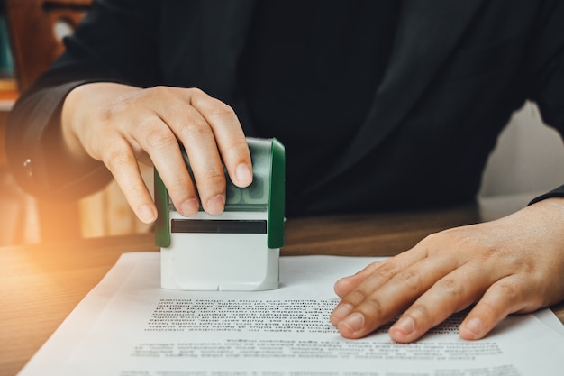 Close-up hand stamping of businesswoman for signing approval on documents