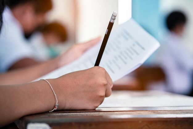 Close up hand of students reading and taking exam sheets\
exercises answer with stress in classroom