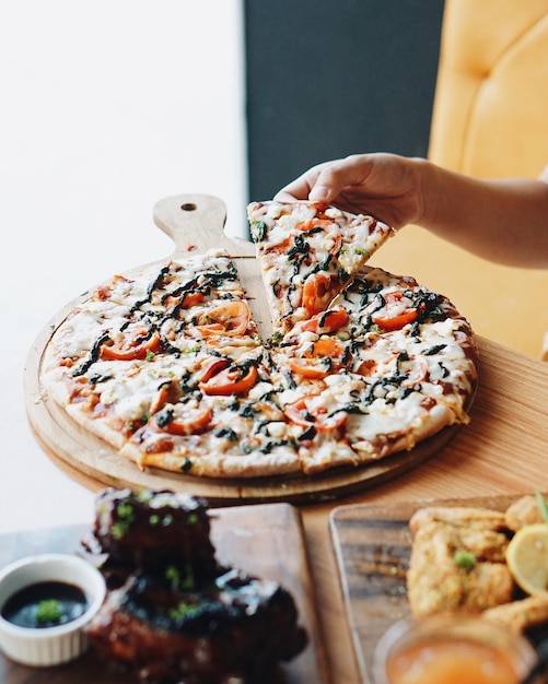 Foto close-up della mano che prende una fetta di pizza