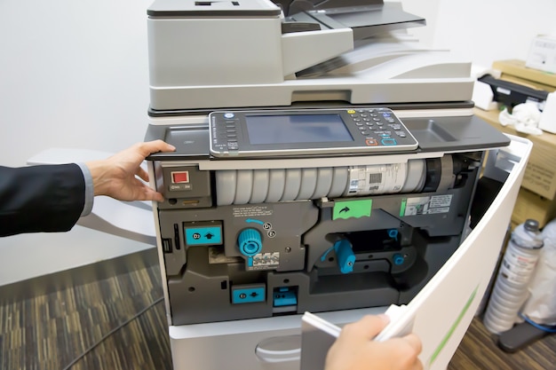 Close up hand of technician to open cover of the photocopier.