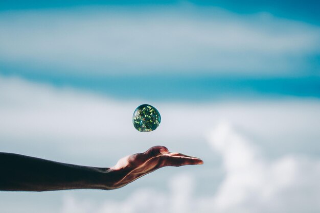 Photo close-up of hand throwing ball against sky