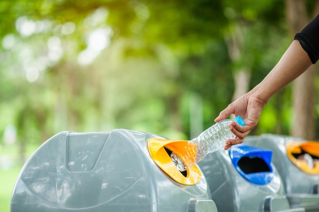 Close up hand throwing empty plastic bottle into the bin.