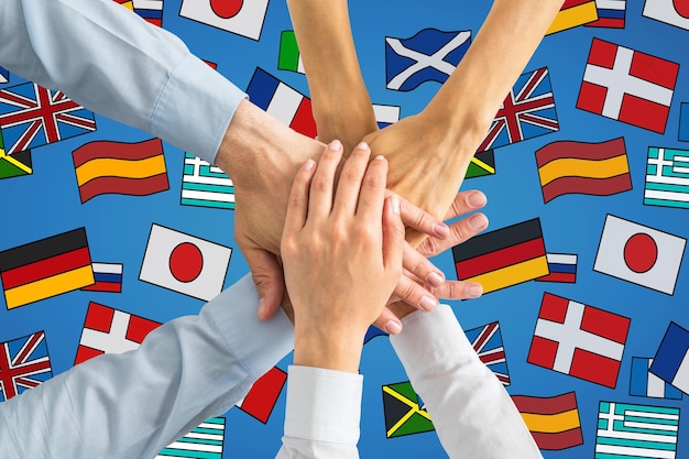 close up of hand on top of each other with abstract colorful flag drawings travel teamwork union translation and language learning concept