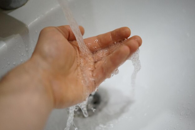 Close-up of hand touching water in bathroom