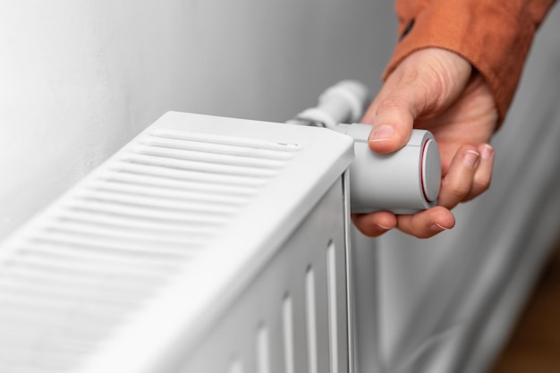 close up of hand turning radiator toggle at home