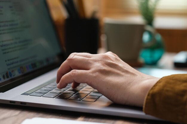 Chiuda sulla digitazione a mano sulla tastiera del laptop quando si sveglia a casa