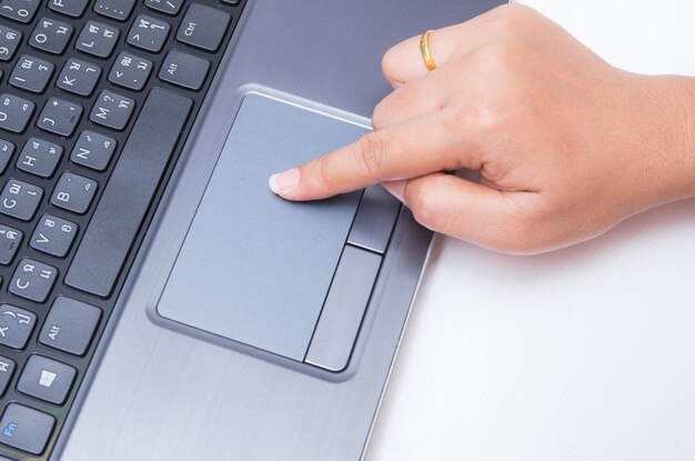 Photo close-up of hand using laptop on desk