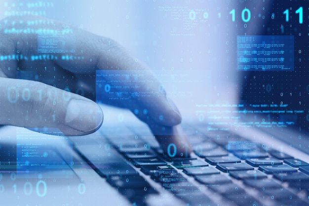 Close up of hand using laptop at desktop with abstract glowing blue coding background Binary code technology data and internet concept Double exposure