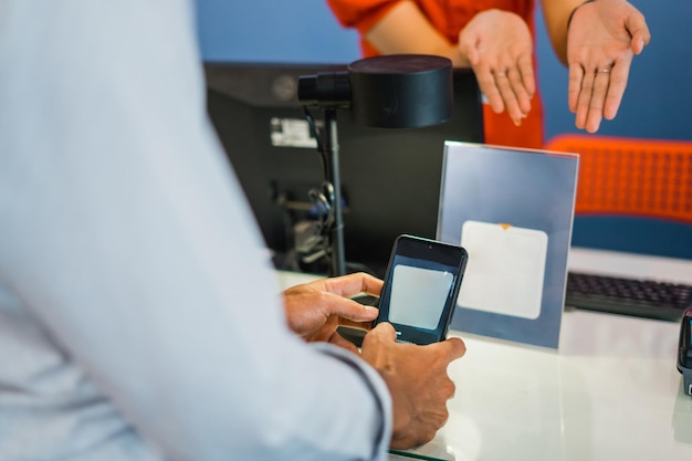 Stretta di mano utilizzando il telefono cellulare per eseguire la scansione del codice a barre durante il pagamento virtuale in negozio