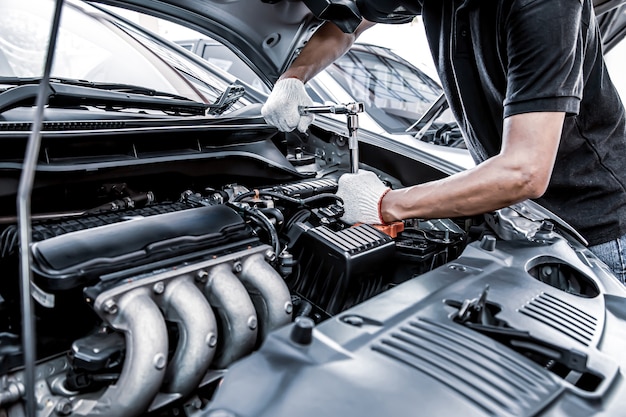 Close-up hand using the wrench to repair car engine.