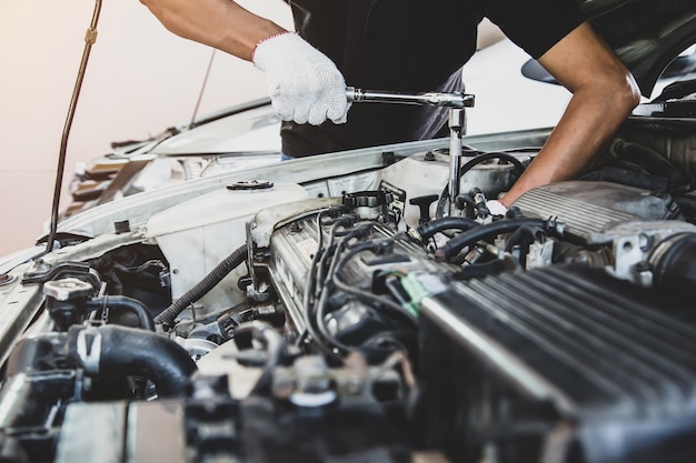 Close-up hand van automonteur gebruikt moersleutel om de motor van een auto te repareren